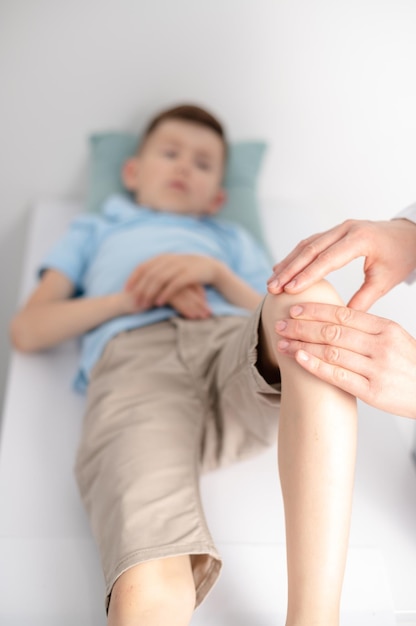 Vrouwelijke arts-orthopedist onderzoekt de knie van jonge jongens in het ziekenhuis of de kliniek Trauma of pijn