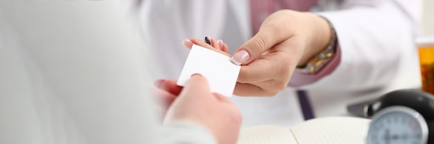 Vrouwelijke arts overhandigt wit visitekaartje aan patiënt