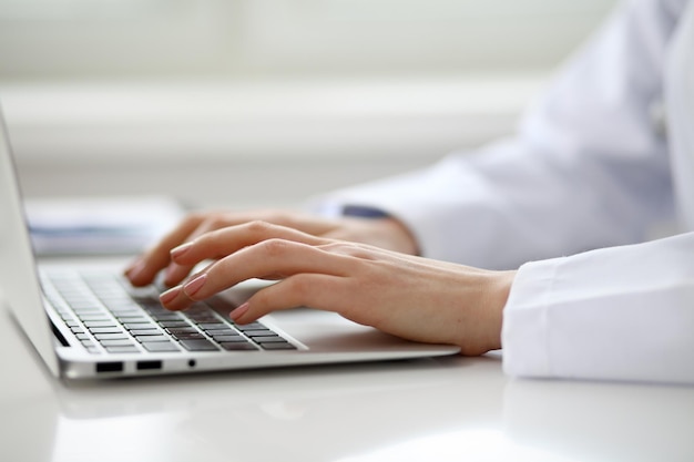 Vrouwelijke arts typen op laptop, close-up.