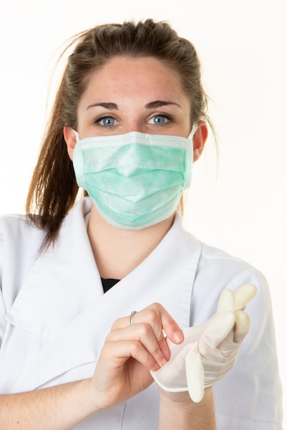 Vrouwelijke arts zet handschoenen plastic op met beschermend gezichtsmasker tegen coronavirus covid-19