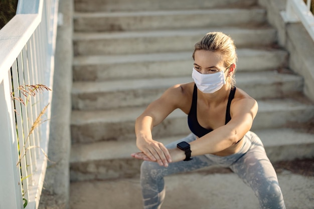 Vrouwelijke atleet die een beschermend gezichtsmasker draagt terwijl ze buiten squats doet