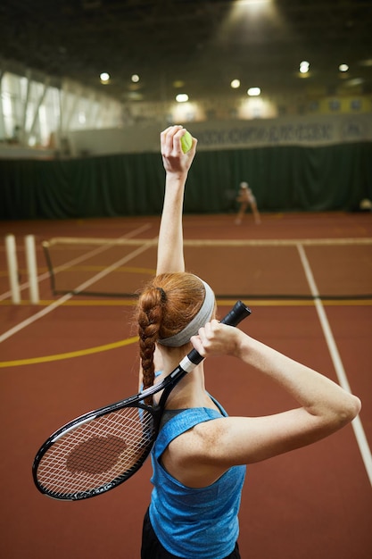 Vrouwelijke atleet die tennisbal gooit om te dienen