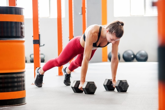 Vrouwelijke atleet doet plank met halters