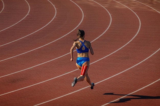 Vrouwelijke atleet loopt op de baan met kinesio tape op haar been