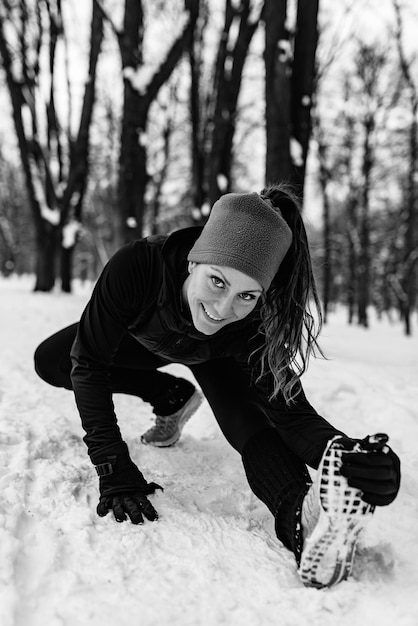 Vrouwelijke atleet trainen in het park op winterdag Muziek luisteren en sporten