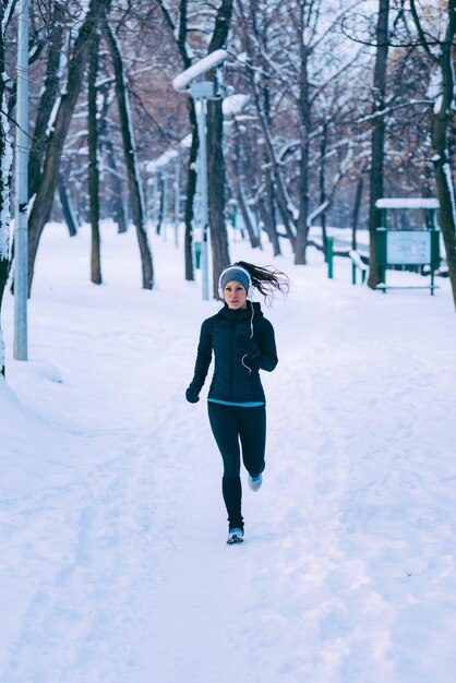 Vrouwelijke atleet trainen in park op winterdag in park