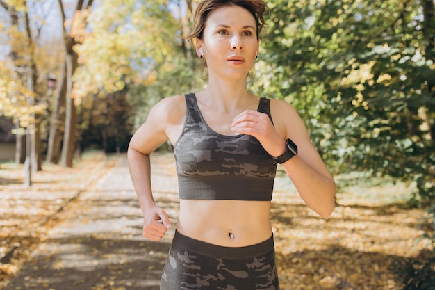 Vrouwelijke atleet vrouw runner dragen draadloze koptelefoon luisteren naar muziek op slimme telefoon