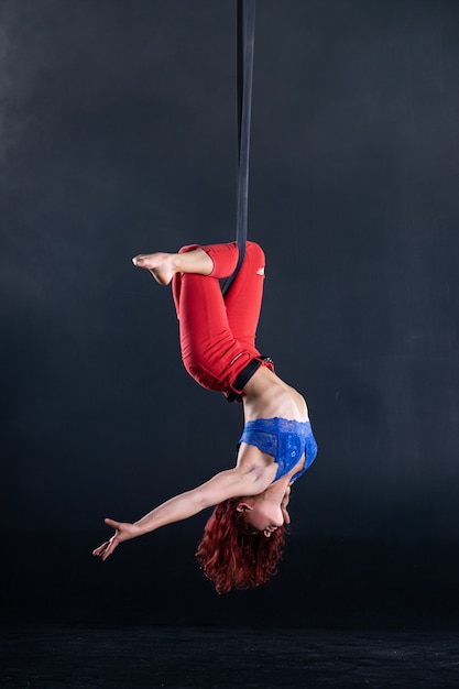 Vrouwelijke atletische, sexy en flexibele luchtcircusartiest met roodharige op luchtbanden