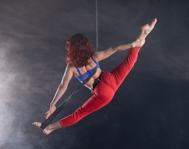 Vrouwelijke atletische, sexy en flexibele luchtcircusartiest met roodharige op luchtbanden