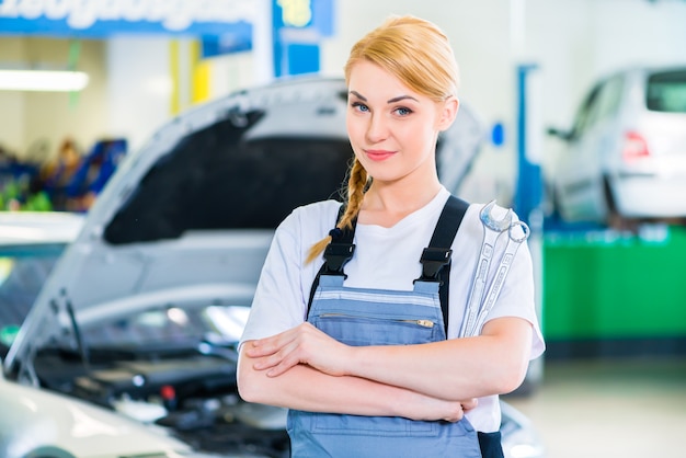 Vrouwelijke automonteur die in autoworkshop werkt