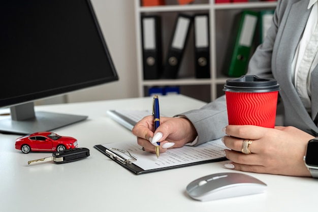 Vrouwelijke autoverkoopmanager bereidt de voorwaarden voor het ondertekenen van een autocontract en verzekering voor