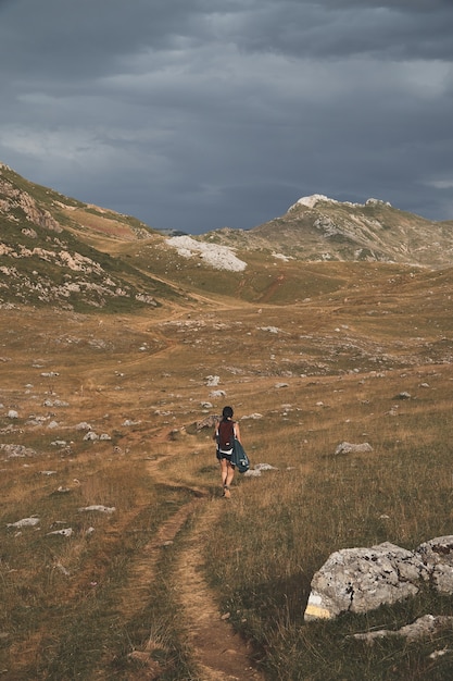 Vrouwelijke backpacker op een grasveld tussen bergen op een bewolkte dag in het natuurpark Somiedo, Spanje