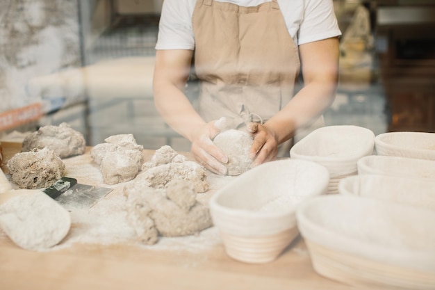 Vrouwelijke bakker die een deeg kneedt in bakkerijwinkel