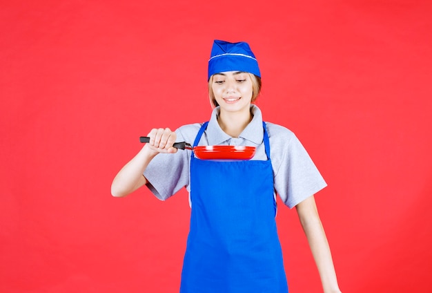 Vrouwelijke bakker in blauwe schort met een tefal koekenpan