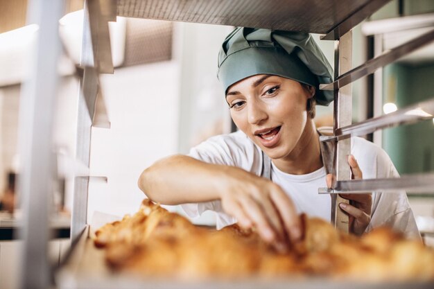 Vrouwelijke bakker in de keuken met croissant