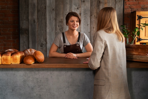 Foto vrouwelijke bakker met klant in de bakwinkel