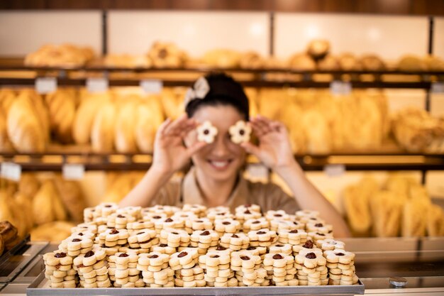 vrouwelijke bakkerijmedewerker die versgebakken snoepjes en koekjes verkoopt in een bakkerij of banketbakkerij