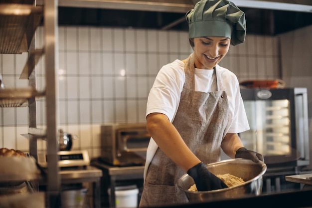 Vrouwelijke banketbakker in de keuken die deeg maakt voor croissants