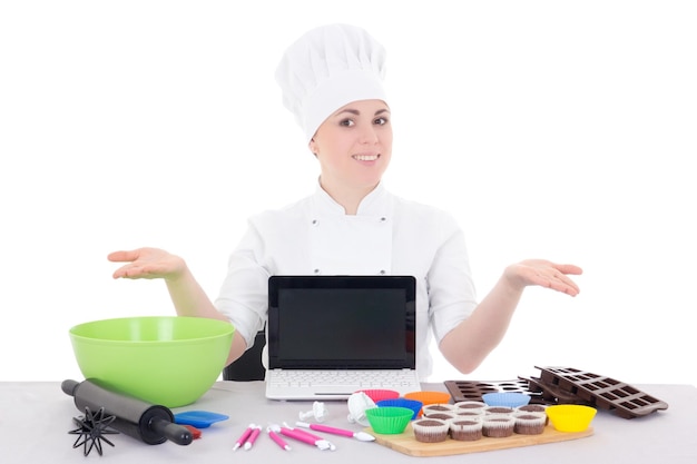 Vrouwelijke banketbakker in kok uniform zitten in de keuken met laptop met copyspace geïsoleerd op witte achtergrond