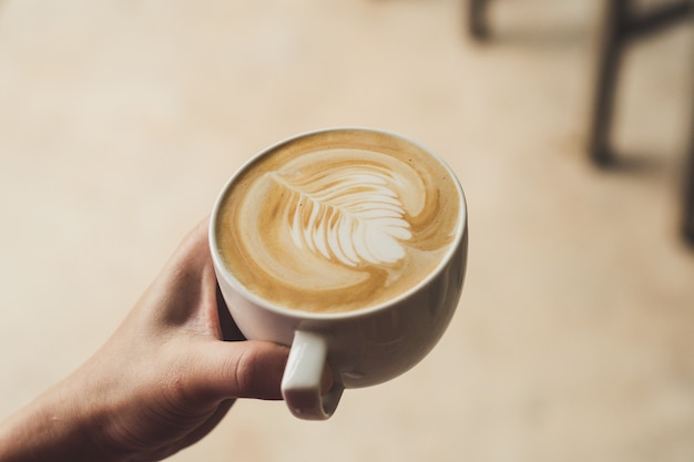 vrouwelijke barista latte art koffie te houden
