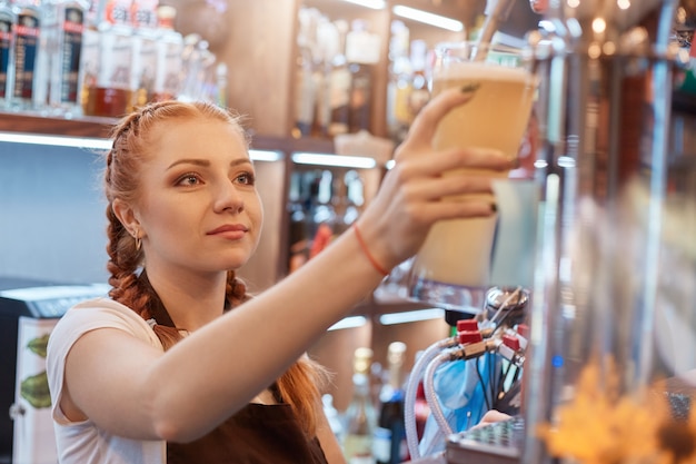 Vrouwelijke barman bier tappen in staaf