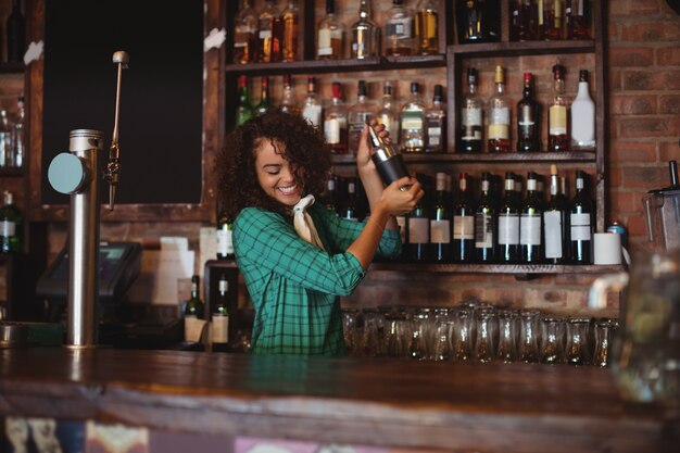 Vrouwelijke barman die een cocktaildrank in cocktailshaker mengt