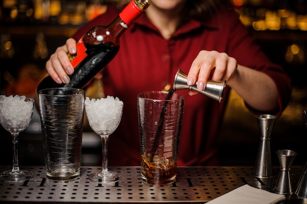 Vrouwelijke barman die een verse en smakelijke alcoholische cocktail maakt