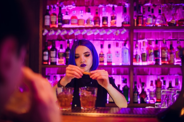 Vrouwelijke barman. meisje met blauw haar. cocktail maken in de nachtbar
