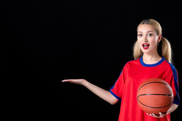 vrouwelijke basketbalspeler in sportkleding met bal op zwarte achtergrond atleet spelletjes spelen