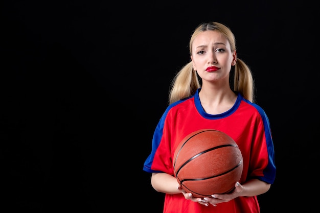 vrouwelijke basketbalspeler in sportkleding met bal op zwarte achtergrondspelatleet speelt