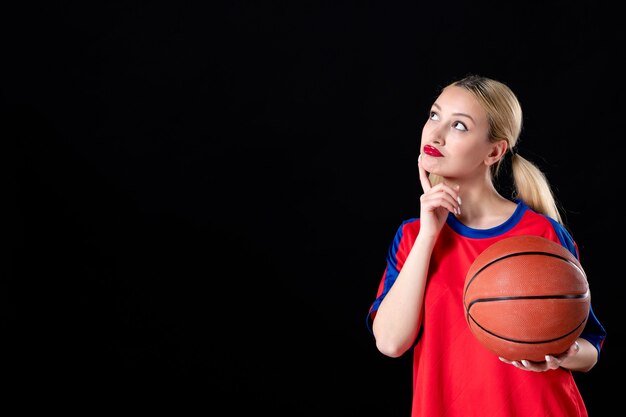 vrouwelijke basketbalspeler met bal denken op zwarte geïsoleerde achtergrond atleet actiespel spelen