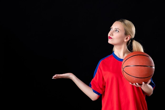 vrouwelijke basketbalspeler met bal op een zwarte geïsoleerde achtergrond atleet play game action