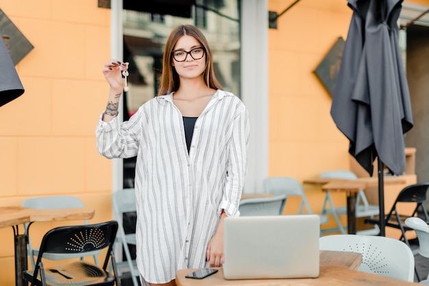 Foto vrouwelijke bedrijfseigenaar met sleutels van koffie en laptop