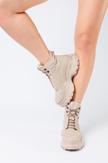 Vrouwelijke benen in beige leren schoenen uit de nieuwe collectie op een witte achtergrond vrouwelijke benen in modieuze schoenen gemaakt van ecoleer lente 2022