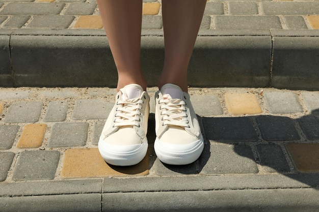 Vrouwelijke benen in sneakers buiten op zonnige zomerdag