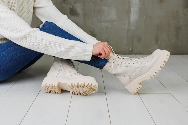 Vrouwelijke benen in spijkerbroek en witte leren laarzen gemaakt van natuurlijk leer Een collectie moderne lenteschoenen voor dames