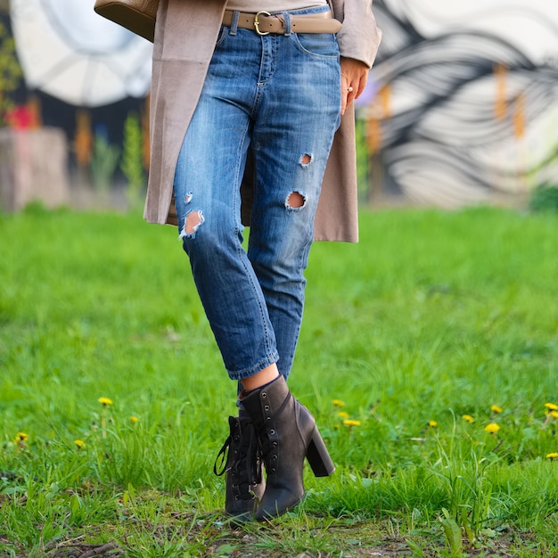 Vrouwelijke benen in vriendjeans die op groen gras stellen