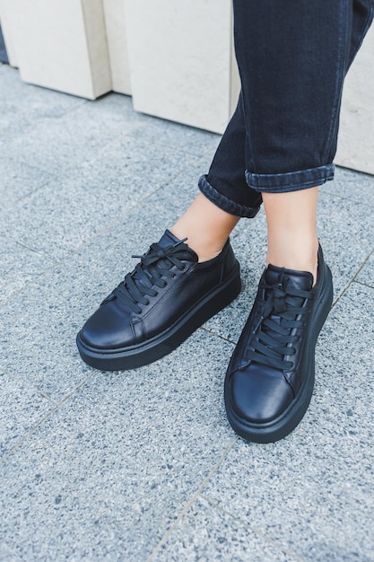Vrouwelijke benen in zwarte jeans en zwarte veterschoenen Zwarte leren schoenen close-up
