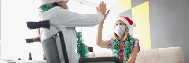 Vrouwelijke bezoekende zus in kliniek familielid zittend in rolstoel high five geven