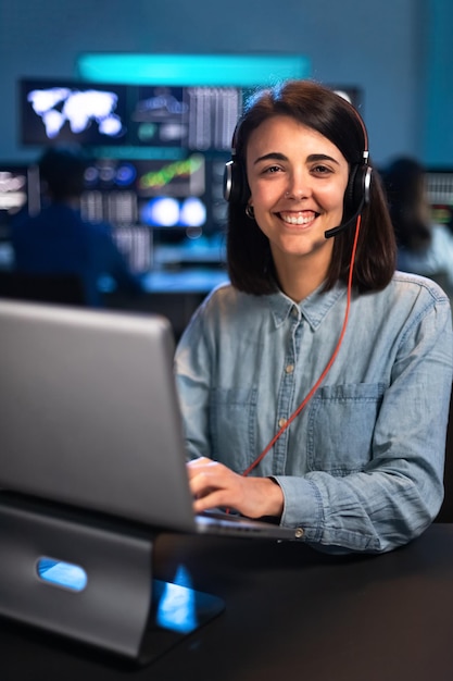 Vrouwelijke blanke financieel analist die op kantoor werkt met laptop en headset die naar camera kijkt Verticaal