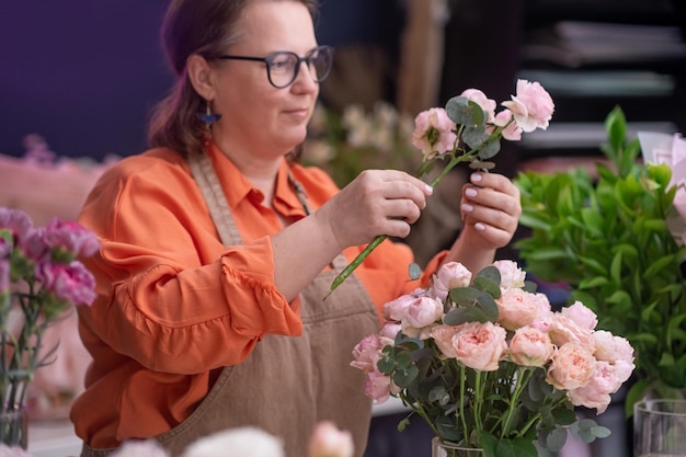 Vrouwelijke bloemdecorateur bloemenontwerper die aan laptop werkt in de studio van de douchewinkel