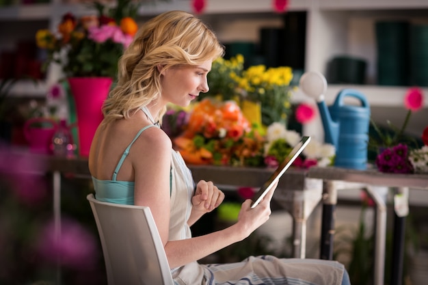 Vrouwelijke bloemist die digitale tablet in bloemistwinkel gebruiken