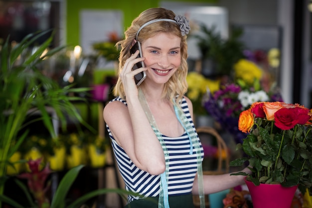 Vrouwelijke bloemist die op mobiele telefoon spreekt