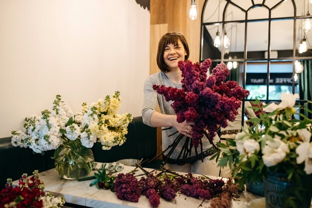 Vrouwelijke bloemist paars lila boeket maken bij bloemenwinkel