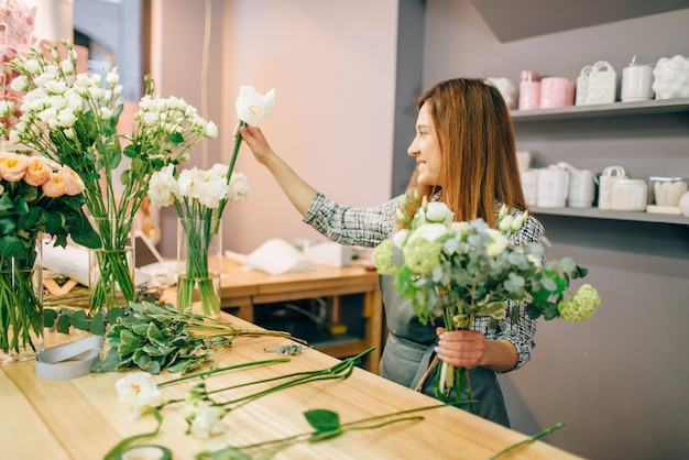 Vrouwelijke bloemist plaatst bloemen in vazen, vers boeket bereidingsproces.