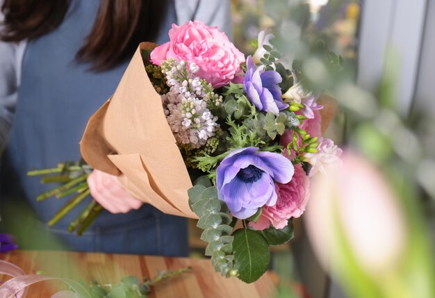 Vrouwelijke bloemist verpakt mooi boeket in inpakpapier bij bloemenwinkel