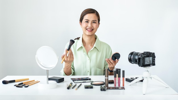 Vrouwelijke blogger is aanwezig make-up tutorial schoonheid cosmetisch beoordelingsproduct en zendt live streaming video uit om online les te geven op het camerascherm in de kantoorstudio