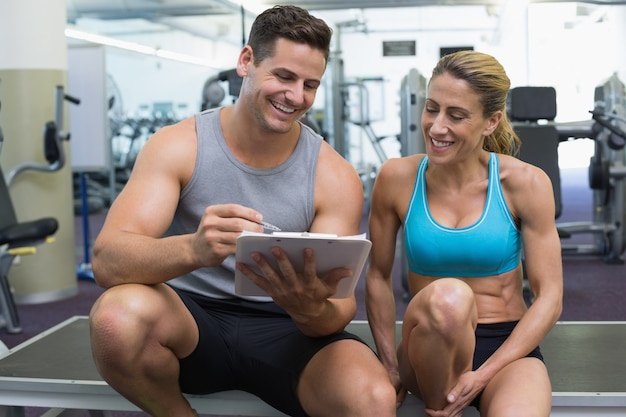 Vrouwelijke bodybuilder zitten met persoonlijke trainer praten