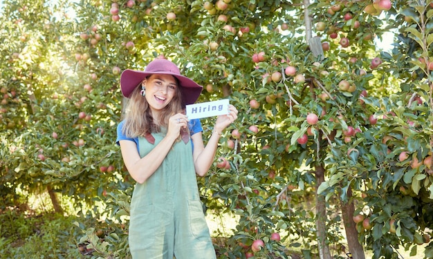 Vrouwelijke boer die arbeiders rekruteert om te helpen met haar opstarten Gelukkige jonge vrouw met een huurteken op een boerderij in de buurt van appelboomgaarden Tekort aan arbeidskrachten in de landbouw, arbeidsmarkt en werkgelegenheid