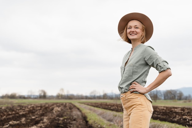 Vrouwelijke boer die trots op het landbouwveld staat